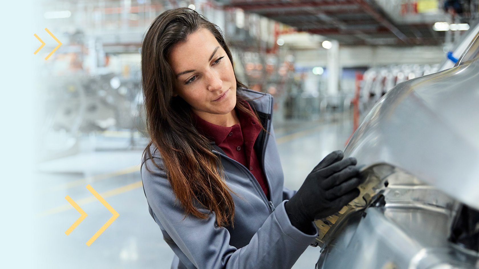 Eine Frau steht neben einem Auto in einer Fabrik eines Automobilherstellers.
